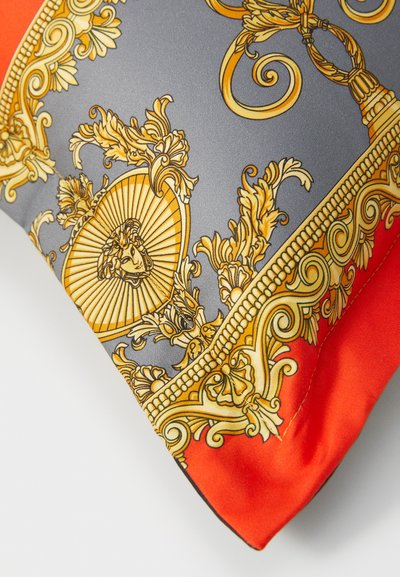 Firkantet dekorativ pute med et grått satengtrekk som har gyldne utsmykninger og en lys orangekant. Jevn tekstur, detaljert design.