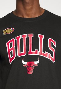 Sort bomulds T-shirt med fed rød "BULLS" tekst og et grafik af et bulls hoved. Inkluderer et logo fra NBA Finals 1996.
