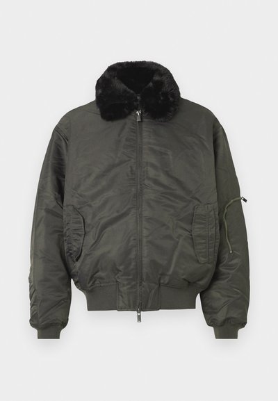 Olivgrüne Bomberjacke mit Kunstfellkragen, Reißverschluss vorne, gerippten Bündchen und Saum sowie seitlichen Taschen und einer Reißverschlusstasche am Arm.