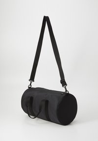 Black duffel bag with a cylindrical shape, made of fabric. Features a top zipper, two side handles, and an adjustable shoulder strap.