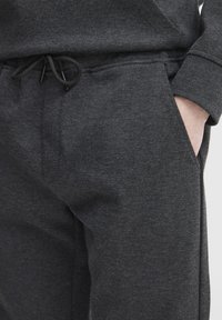 Dark gray sweatpants featuring a textured fabric, elastic waistband with drawstring, and side pockets.