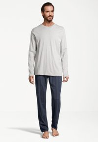 Chandail gris à manches longues et pantalon de pyjama rayé bleu marine. Le tissu semble doux avec une coupe décontractée et des coutures minimales. Pas de chaussures.