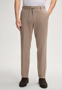 Beige broeken met een textuurafwerking, voorzien van een elastische tailleband, zijzakken en een recht model. Gecombineerd met donkere suède laarzen.