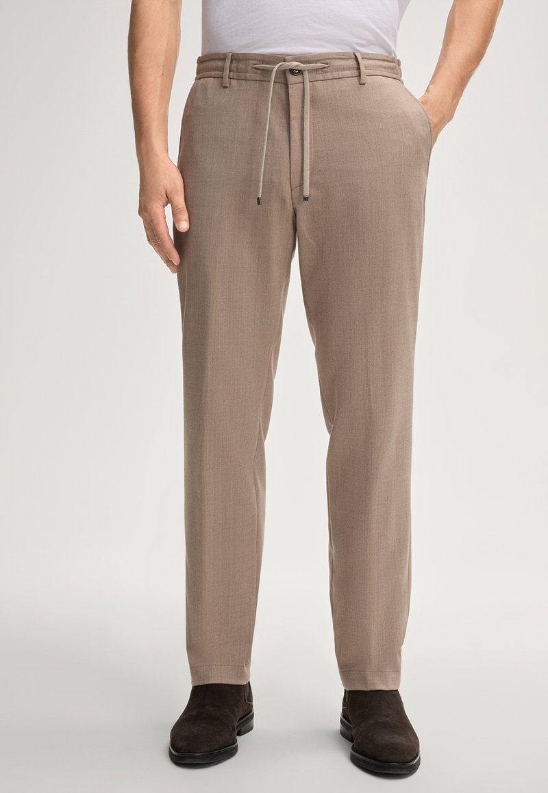 Beige broeken met een textuurafwerking, voorzien van een elastische tailleband, zijzakken en een recht model. Gecombineerd met donkere suède laarzen.