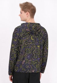 Giacca con cappuccio in tessuto nero con motivi geometrici colorati in viola, giallo e rosa; presenta una vestibilità morbida e maniche lunghe.