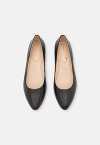 Ballerines en cuir noir avec bout pointu, texture lisse et design minimaliste. Semelles intérieures beige avec logo de la marque.