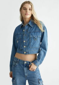 Giacca di jeans cropped di un azzurro chiaro con bottoni dorati, due tasche frontali e colletto classico. Tessuto testurizzato, design aderente.