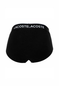Culotte en coton noir de forme ronde. Dotée d'une large ceinture affichant "LACOSTE" en blanc. Texture lisse avec un minimum de détails.