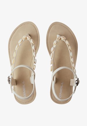 Sandali piatti bianchi con un'accento a forma di conchiglia sulle cinghie, una soletta beige liscia e una fibbia regolabile alla caviglia.