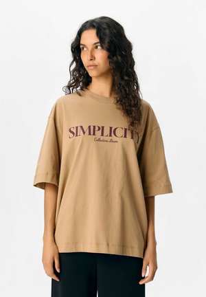 Bruine oversized t-shirt met korte mouwen, voorzien van de tekst "SIMPLICITY" en "Collectors team" in bordeauxrood. Zachte katoenstof.