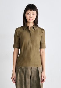 Oliven grønn ribbet polo skjorte med krage, knappefront og rullede korte ermer. Strukturert stoff i en tettsittende design.