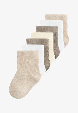 Seitse paari soonikkoega beebisokke beežis, valges, kreemis ja helepruunis, paigutatud hajutatult kattuvasse mustrisse.