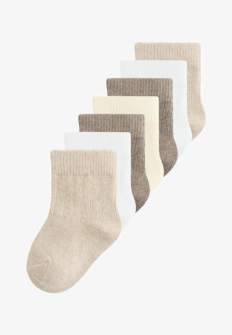 Zeven paar geribbelde babysokken in beige, wit, crème en lichtbruin, gerangschikt in een gevarieerde overlappende opstelling.