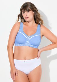 Světle modrá podprsenka s puntíkovaným vzorem a bílými akcenty, s širokými ramínky a malou mašlí uprostřed. V kombinaci s bílými kalhotkami.
