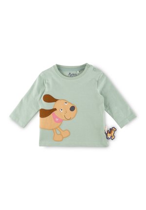 Chemise bébé à manches longues vert clair avec une application représentant un chien de dessin animé souriant et un petit jouet en forme de chien attaché en bas à droite.