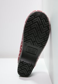 Scarpa rossa in gomma con pois bianchi; suola nera testurizzata con motivo a zigzag; presenta logo impressa e taglia 39.