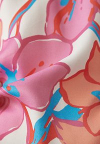 Glatte Stoffe mit einem floralen Muster, das große rosa und orangefarbene Blumen zeigt, akzentuiert durch blaue Linien auf einem weißen Hintergrund.