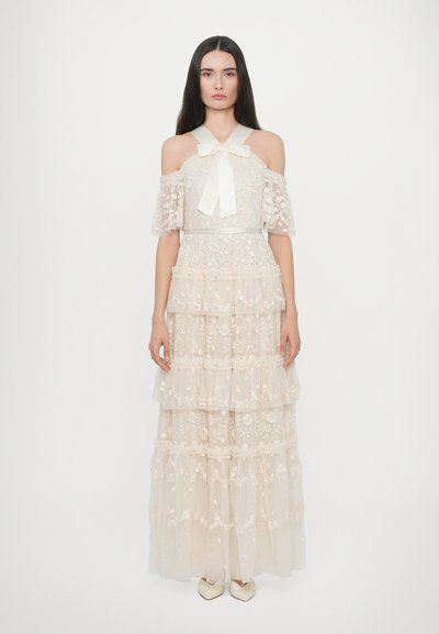 Robe en dentelle décolletée avec des manches à volants, jupe superposée, ruban ivoire à l'encolure, broderies florales et texture transparente.