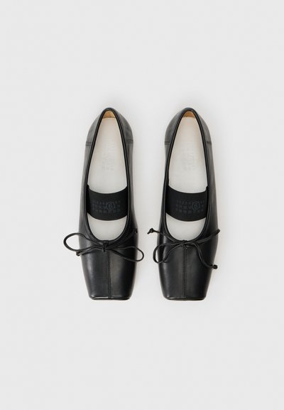 Ballerines en cuir noir avec bouts carrés, bords arrondis et détails de laçage. Texture lisse avec un intérieur rembourré et un soutien de cheville élastique.