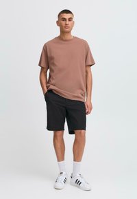 Brown cotton t-shirt, black shorts, white socks with black stripes, and white sneakers. Simple, casual design, standard fit, and solid colors.