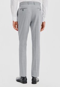 Slim-fit szare spodnie dresowe wykonane z teksturowanej tkaniny, z dwiema tylnymi kieszeniami zapinanymi na guziki i gładkim pasem.