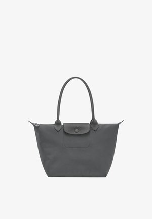 Black tote bag with long handles, top zipper, and front flap pocket with button closure on a white background.