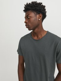 Camiseta de manga corta gris oscuro hecha de una suave mezcla de algodón, con un corte relajado y un sutil detalle en el escote. Sin patrones o logotipos visibles.
