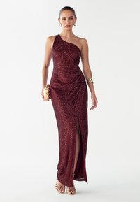 Pikk burgundia värvi litridest kleit ühe õlaga disainiga, drapeeritud detailide ja reie kõrguse lõhikuga. Sobitatud kuldse väikese kotiga ja rihmikute kontsadega.