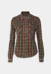 Camicia a quadri in verde, nero e rosso. Dotata di colletto, due tasche sul petto e chiusure a bottoni. Maniche lunghe con polsini abbottonati.