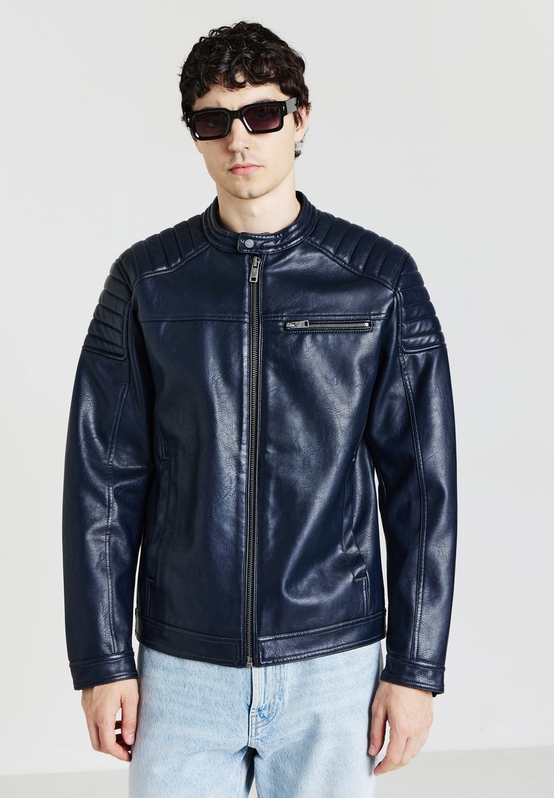 Veste en cuir bleu marine au design ajusté, fermeture éclair, accents matelassés aux épaules et petite poche poitrine ; texture lisse.