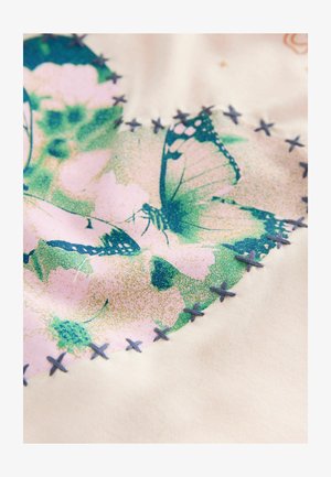 Audinys su spalvinga drugelio ir gėlių raštu rožinėje ir žaliai, su mėlynomis siūlų akcentais aplink kraštus.