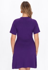 Abito corto viola con maniche corte, dalla gonna svasata e corpino aderente, realizzato in un tessuto morbido, con un design semplice e pulito e colletto rotondo.