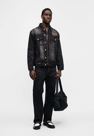 Μαύρο τζιν μπουφάν με ελαφρά ξεθώριασμα, με κουμπιά κλεισίματος και δύο τσέπες στο στήθος. Συνδυασμένο με σκούρα τζιν παντελόνια και μαύρη τσάντα.