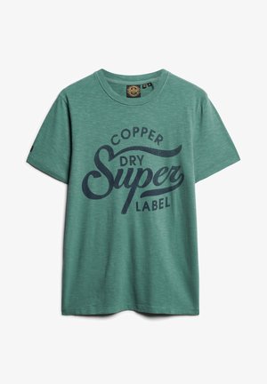 T-shirt verde in cotone a maniche corte con scollo tondo e scritta blu scuro "Copper Dry Super Label" stampata sul davanti.