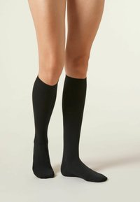 Schwarze kniehohe Socken aus glattem Stoff, mit schmalem Design, geripptem oberen Bund und ohne sichtbare Muster oder Akzente.