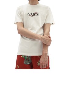 Krémové tričko s krátkým rukávem s logem "VANS" a grafickými detaily, nošené s vzorovanými červenými šortkami. Měkký bavlněný materiál, volný střih.