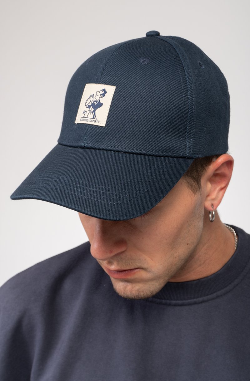 Cappello blu navy con design strutturato, caratterizzato da un patch del logo cucito sulla parte anteriore. Il tessuto ha una texture liscia e dettagli di cucitura visibili.