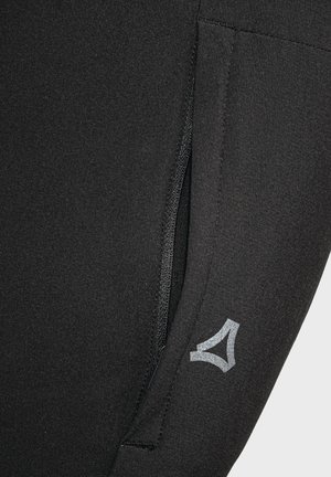 Black athletic leggings featuring a zippered pocket and a reflective logo detail on the lower side. Soft, smooth texture.