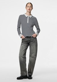 Tamsiai mėlynos ir baltos spalvos ilgomis rankovėmis striped marškiniai su apykakle ir mygtukų užsegimu, derinami su laisvais pilkais džinsais ir juodais batais.