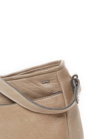 Beige leren schoudertas met een textuurafwerking, voorzien van een gestikt bovenrand en een eenvoudig metalen logo aan de zijkant. Verstelbare schouderriem.