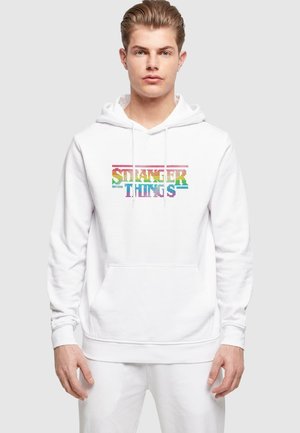 White hoodie featuring "Stranger Things" text in a multicolored pixelated design, with a front pocket and drawstring hood.