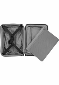 Interior de maleta gris con compartimento con cremallera, correas en forma de X para asegurar objetos, textura suave y patrón en el forro.