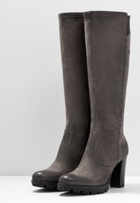 Bottes montantes hauteur genou en suédine grise, à talon bloc, avec des détails de coutures texturées, un bout arrondi et une semelle en caoutchouc crantée pour une meilleure adhérence.