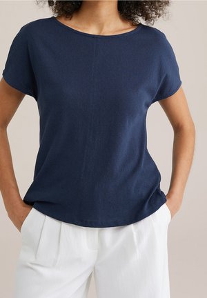 Mørkeblå kortærmet top med rund halsudskæring, blød tekstur og let afslappet pasform, båret med lyse, løstsiddende bukser.