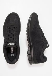 Svarta sportskor med ovandel i mesh och syntetmaterial, rund tå, vadderad tunga och gummisula med ett mönstrat slitbanedesign.