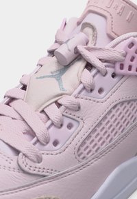 Κοντινό πλάνο ροζ αθλητικού παπουτσιού με υφασμένα κορδόνια, διάτρητη πλαϊνή επιφάνεια και τόνους πλαστικού κλειδώματος κορδονιών στη μαξιλαρωμένη γλώσσα.