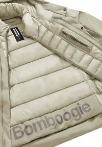 Giacca a vento beige con interno trapuntato, dotata di tasca sul petto e di una grande stampa "Bombogie" sul lato. Tessuto liscio e leggero.