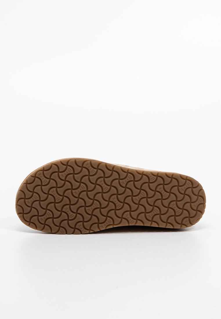 Bruine rubberen zool met een golvend patroon, vlak ontwerp en gestructureerd oppervlak; heeft het logo van het merk in het midden.