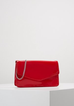 Blank rød rektangulær clutch med en sølvkæde, der ligger på en hvid overflade mod en ensartet baggrund.