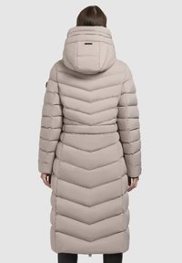 Long beige puffer coat with a chevron quilted pattern, hood, and fitted sleeves. Smooth texture, tailored design, and back accent.